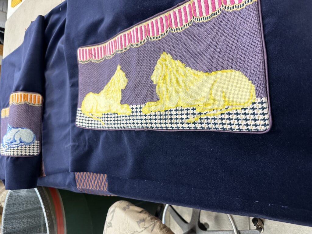 A dark blue textile with a woven panel featuring yellow and blue abstract shapes, geometric patterns, and red stripes, displayed on a table.